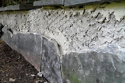 Lange gemauerte Sitzbank - Die Naturstein-Verkleidung mit Polygonalplatten ist stark beschädigt